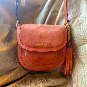 Michael Kors cinnamon suede crossbody bag / tassel detail. Two outer pockets.